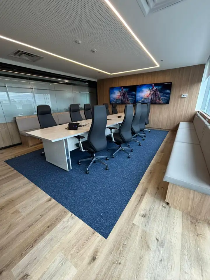 Sala de juntas con tapete de alfombra modular Flow azul sobre piso de madera